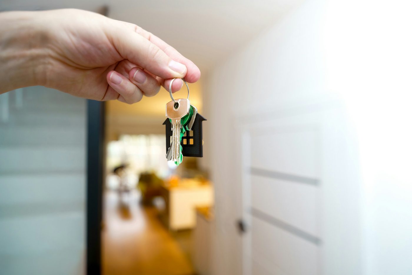 A person holding house keys at the bright entrance of a new home